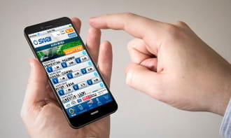 Delle mani reggono uno smartphone con la app mobile di SNAI