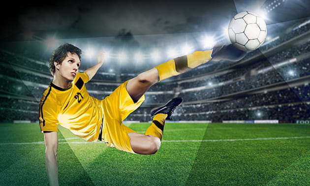 Un calciatore compie una sforbiciata in uno stadio affollato durante una partita in notturna