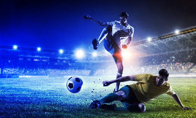 Un contrasto di gioco tra due calciatori durante una partita in notturna